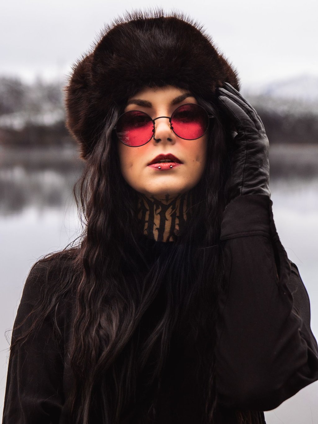 Kreatives Portrait mit Fellmütze und roter Sonnenbrille