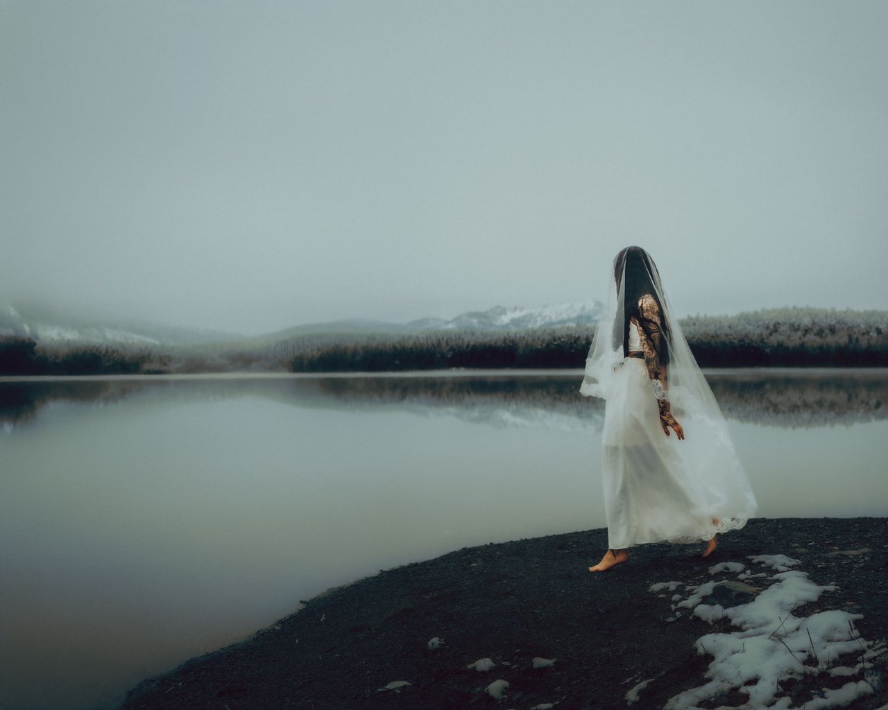 Figur im weißen Kleid am nebligen See