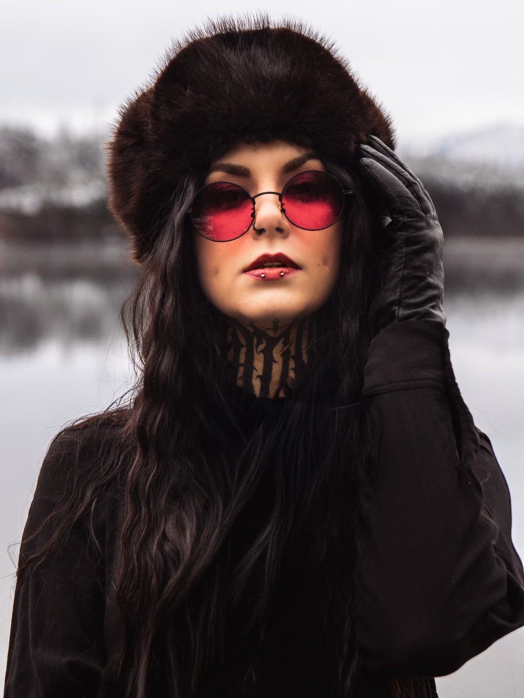 Portrait mit Fellmütze und roter Sonnenbrille am See