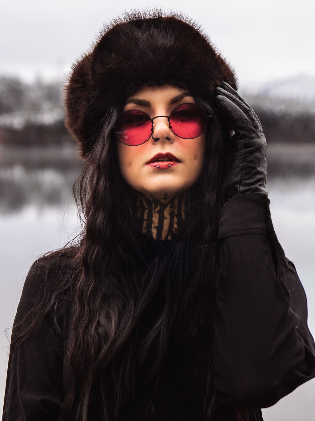 Portrait mit Fellmütze und roter Sonnenbrille am See